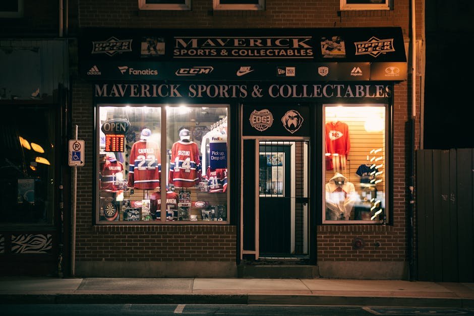 Nighttime view of Maverick Sports & Collectables shop displaying sports jerseys and memorabilia.